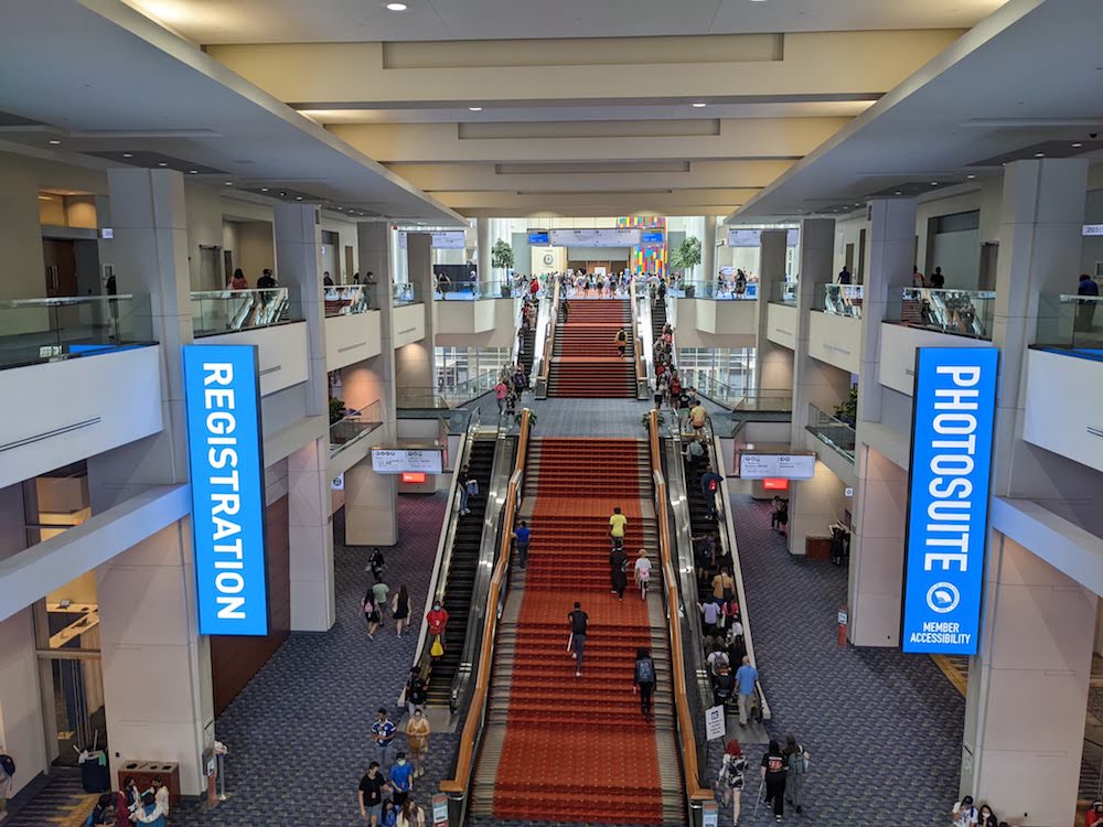 The Walter E. Washington Convention Center. A large redstaircase cuts through the middle, with escalators on each side. Blue signs saying "Registration" and "Photosuite" show that this is Otakon.