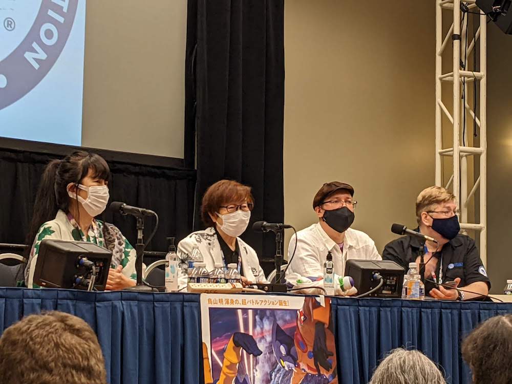 A photo of Kakinuma Shino and Furukawa Toshio at their panel. Next to them is the host and the interpreter.