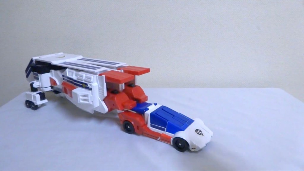 An image of the original 1990s toy version of Exkizer in car form attached to the King Roder as a large trailer. The trailer is about twice the size of the car.