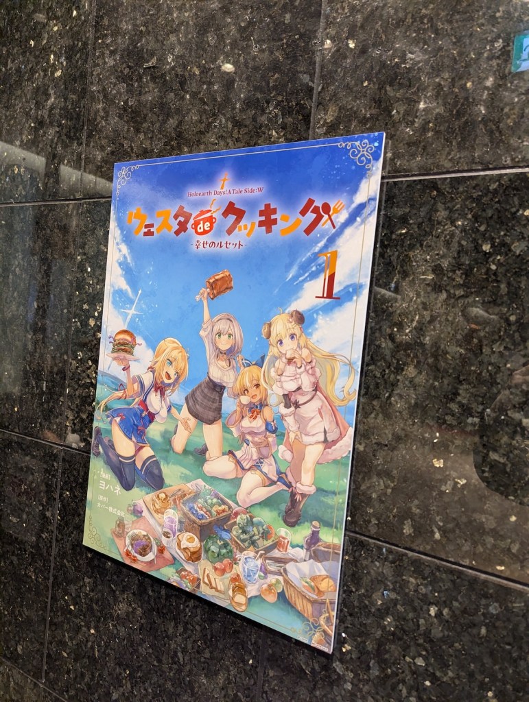 A poster using the cover of Vesta de Cooking Volume 1. It shows Haachama, Noel, Flare, and Watame enjoying a picnic in front of a vast, blue sky.