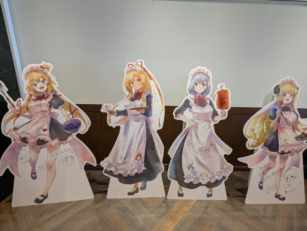 Standees of Haachama, Flare, Noel, and Watame dressed as maids. 
