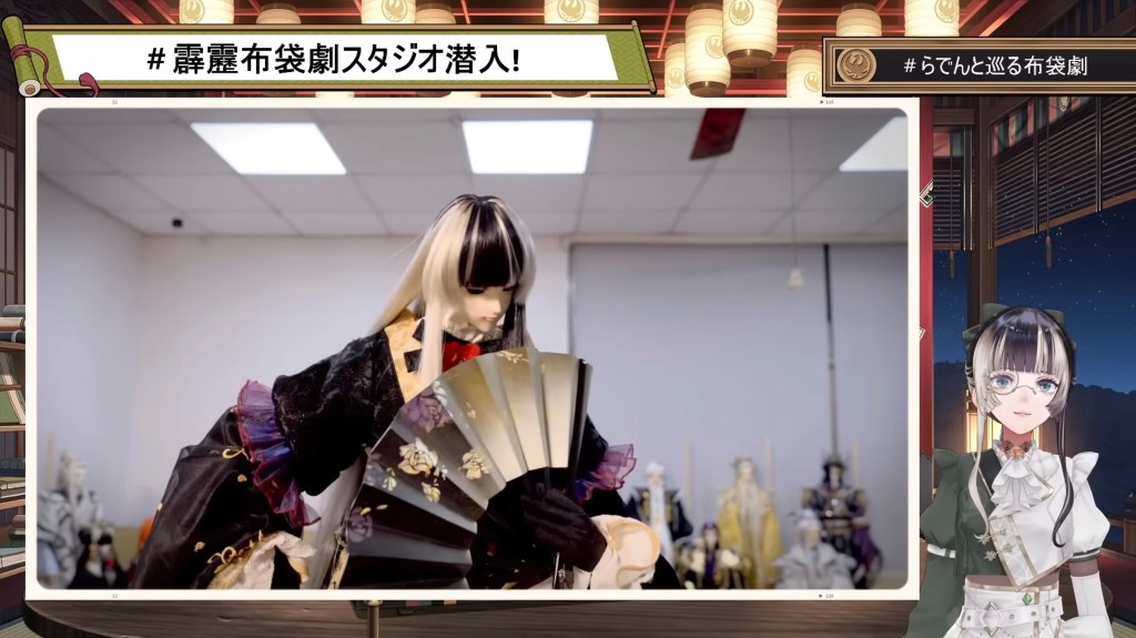 Juufuutei Raden watching a video of herself, which has an elaborate puppet version of her on screen.